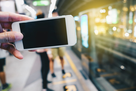 Smartphone black screen in hand at train station blurred peopleの写真素材
