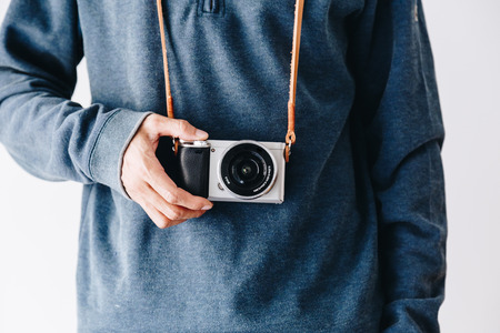 Photographer man with leather camera strap and mirrorless camera on white backgroundの写真素材