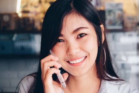 Smiling business casual women talking on cellphone in vintage coffee shopの写真素材