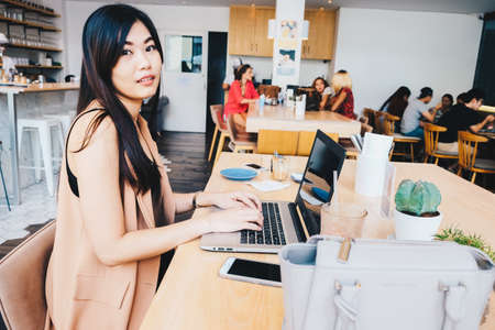 Smiling business women wear casual suit using laptop for business communication in modern loft cafeの写真素材