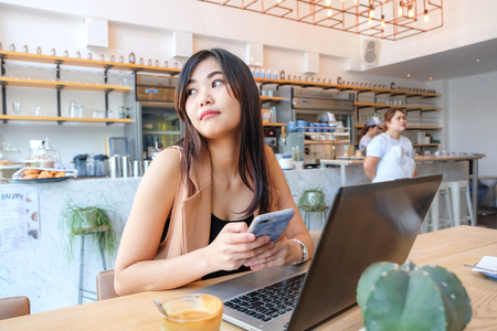 Business women use laptop in coffee shop with blur people background, Business communication with technologyのeditorial素材