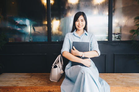 Women holding laptop computer sitting in vintage cafe, Business womenの写真素材