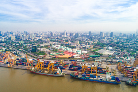 Port with city logistics and transportation of Container Cargo ship and Cargo plane with working crane bridge in shipyard at morningの写真素材