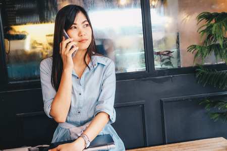 Business asian women use laptop sitting in vintage cafe with pine treeの写真素材