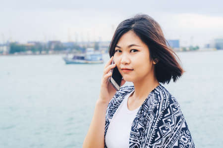 Beautiful asian women using smartphone on the beach sea backgroundの写真素材