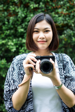 Hipster photographer women with camera on green leaf backgroundの写真素材