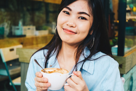 Beautiful asian women sitting in vintage cafe smiling to camera