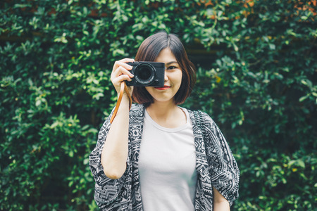 Hipster photographer women with camera on green leaf background
