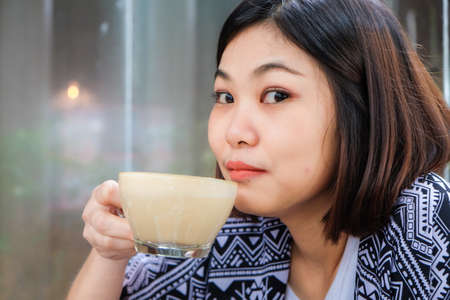 Asian women drinkking latte coffee in art cafeの写真素材