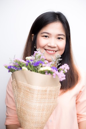 Beautiful asian women with colourful flower bouquet smiling isolated on white backgroundの写真素材