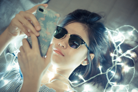 Beautiful women relaxing on cozy bed with light bedtime activityの写真素材