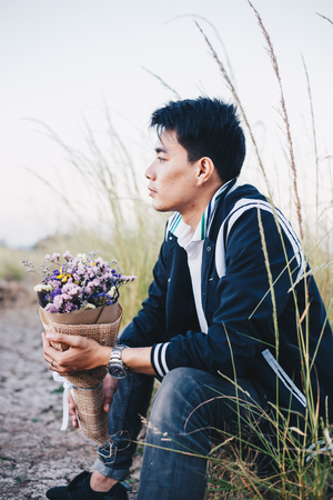 Portrait of young asian handsome man in meadow with dry flowerの写真素材
