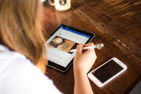 Happy young asian business women using tablet and cellphone while sitting in coffee shop on wood tableの写真素材