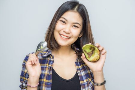 Happy young beautiful women holding avocado for eat on white backgroundの写真素材