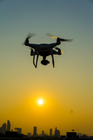 Silhouette quadcopter flying on the city building sunsetの写真素材