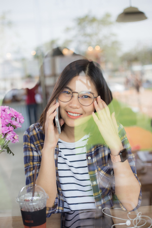 Business women with phone sitting in cafe through mirrorの写真素材