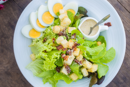 Caesar salad dress bread with green vegetable and egg healthy food on wood tableの写真素材
