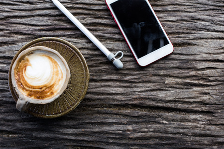 Smartphone with cup of coffee on wood background business objectの写真素材