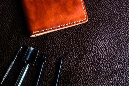 Tool making genuine leather wallet craftsmanship workshop flatlay on cowhideの写真素材