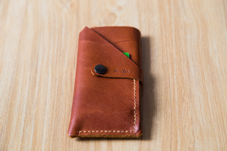 Brown genuine leather passport bag case on wood baclground craftsmanship