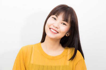 Portrait of asian beautiful smiling women yellow shirt on white background studio shotの写真素材
