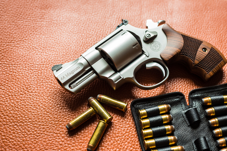 Revolver handgun with ammunition bullet on leather backgroundの写真素材