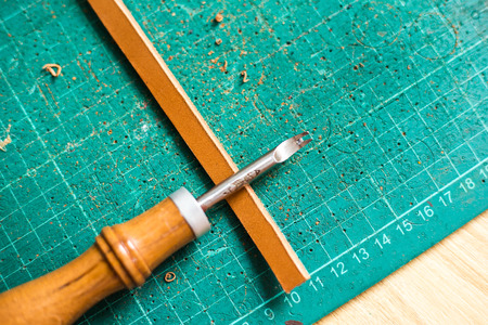 Leather craftsmanship working panel with metal cut on leather object, Leather work