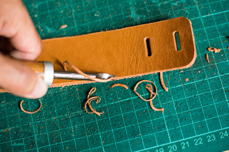 Leather craftsmanship working panel with metal cut on leather object, Leather work