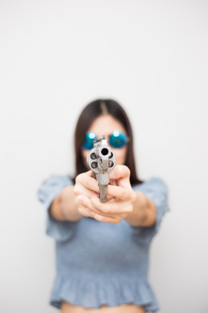 Smart beautiful women pointing revolver gun into camera on white backgroundの写真素材