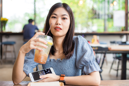 Beautiful women wear smart watch sitting in cafe drinking juice, Asian womenの写真素材