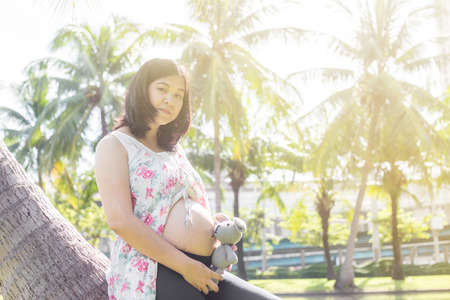 Young happy pregnant women relaxing with doll in park outdoor, The boy comingの写真素材