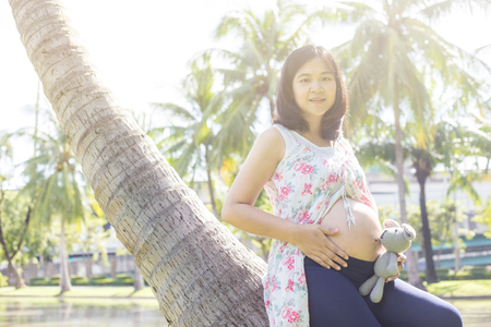 Young happy pregnant women relaxing with doll in park outdoor, The boy comingの写真素材