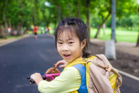 Cute asian girl having fun outdoor ride bicycle in park, Hobby of child