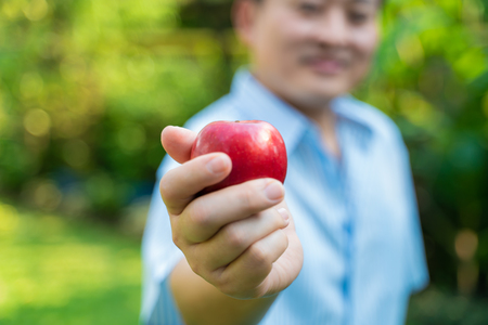 Senior man with apple fruit in green park positive thinkingの写真素材