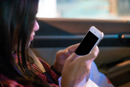 Beautiful asian women use smartphone in car at night chat with friendの写真素材