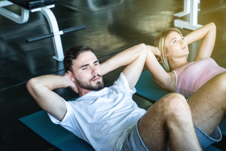 Couple of caucasian sport attractive man and women make sit up crunch exercise in gym