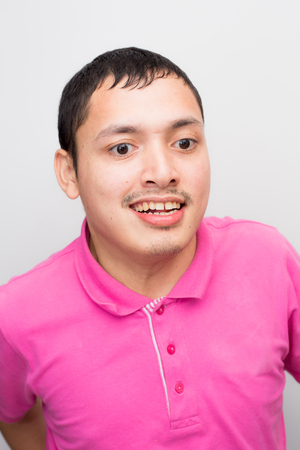 Young handsome disable man smiling on white background pink shirtの写真素材