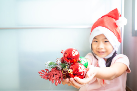Child girl enjoying with christmas santa costume playing christmas ball and decoration giftの写真素材