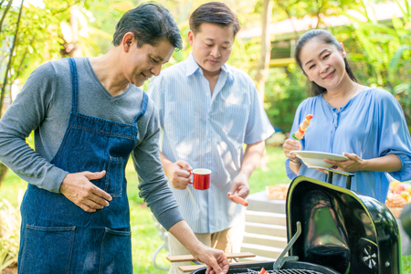 Group of people picnic party in home garden with bbq food drinking and eating