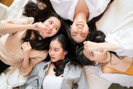 Happy beautiful young asian women talking and use phone together on bed smiling womenの写真素材