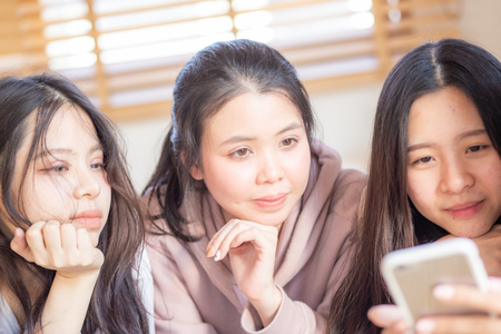 Group of cheerful women using smartphone shopping online together in houseの写真素材