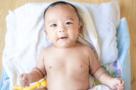 Smiling adorable infant 3 month baby lying on blanket with rubber toy biteの写真素材