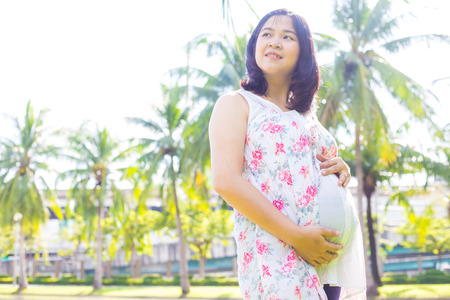 Asian pregnant women posing in city public green park enjoy nature