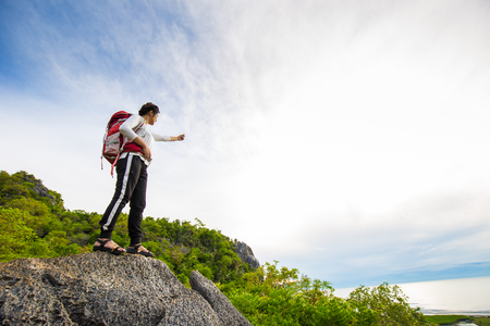 Happy hiking woman stand on top of mountain with backpack enjoy sunriseの写真素材