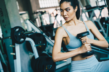 Wellbeing smart asian sport women lifting dumbbell in gym, Healthy lifestyleの写真素材
