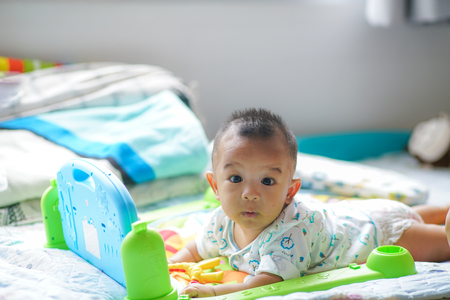 Adorable infant toddler boy playing toy on bed 4-6 month babyの写真素材