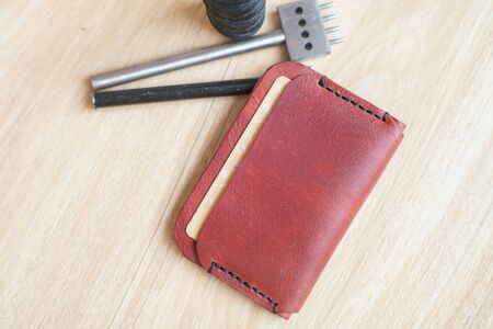 Genuine leather id card holder with tool on wood background