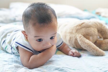Toddler smiling asian child boy lying on bed enjoy with dollの写真素材