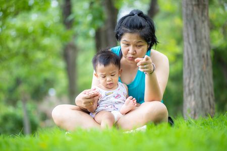 Mother playing with baby boy on green grass recreation timeの写真素材