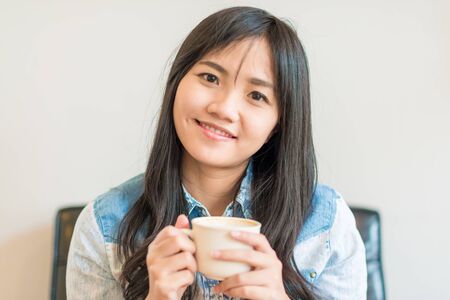 Beautiful asian women hold hot coffee cup in cafe drinking latte coffee